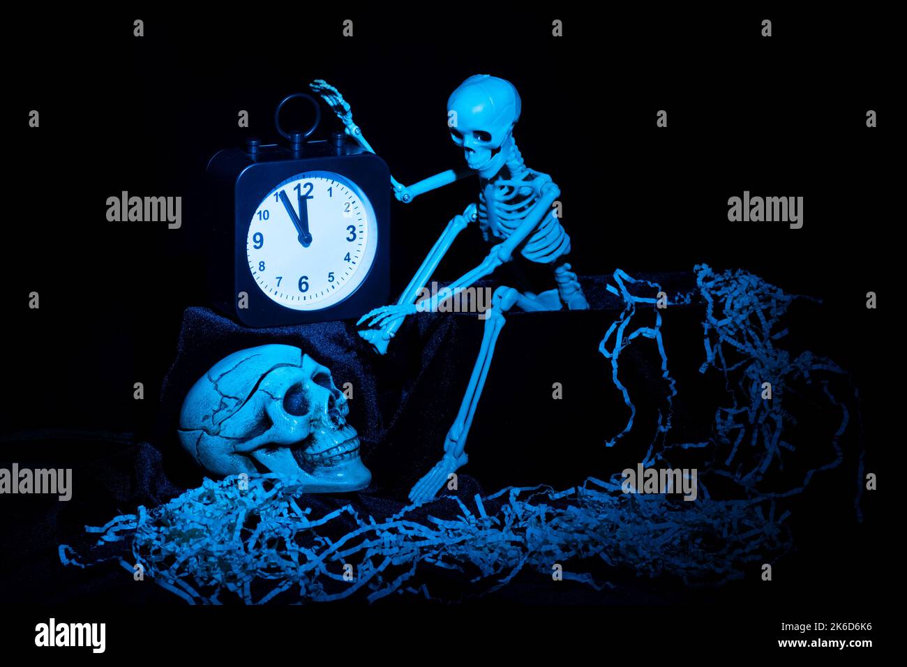Un squelette se réveillant, rampant hors de la tombe et en éteignant le réveil, un crâne sur un fond noir avec des ordures teintées en bleu. La veille de Banque D'Images