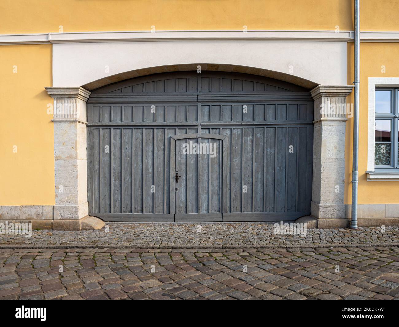 Grande porte d'entrée en bois dans un ancien bâtiment. Porte d'une cour intérieure assez grande pour les voitures. Architecture dans une zone rurale. Planches de bois altérées. Banque D'Images