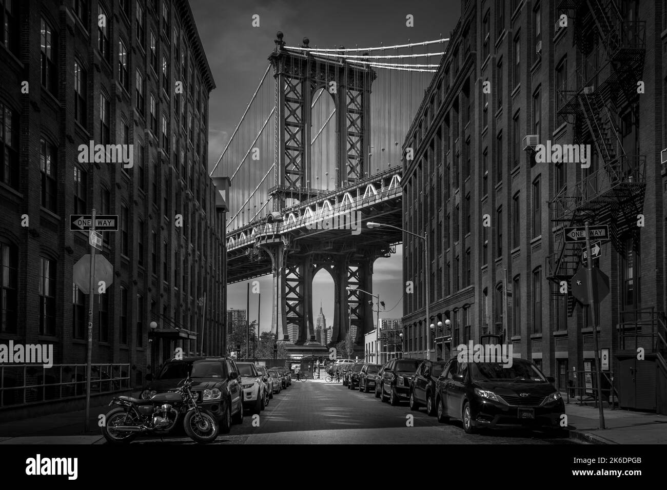 Une échelle de gris de bâtiments urbains et de voitures garées avec Manhattan Bridge en arrière-plan Banque D'Images