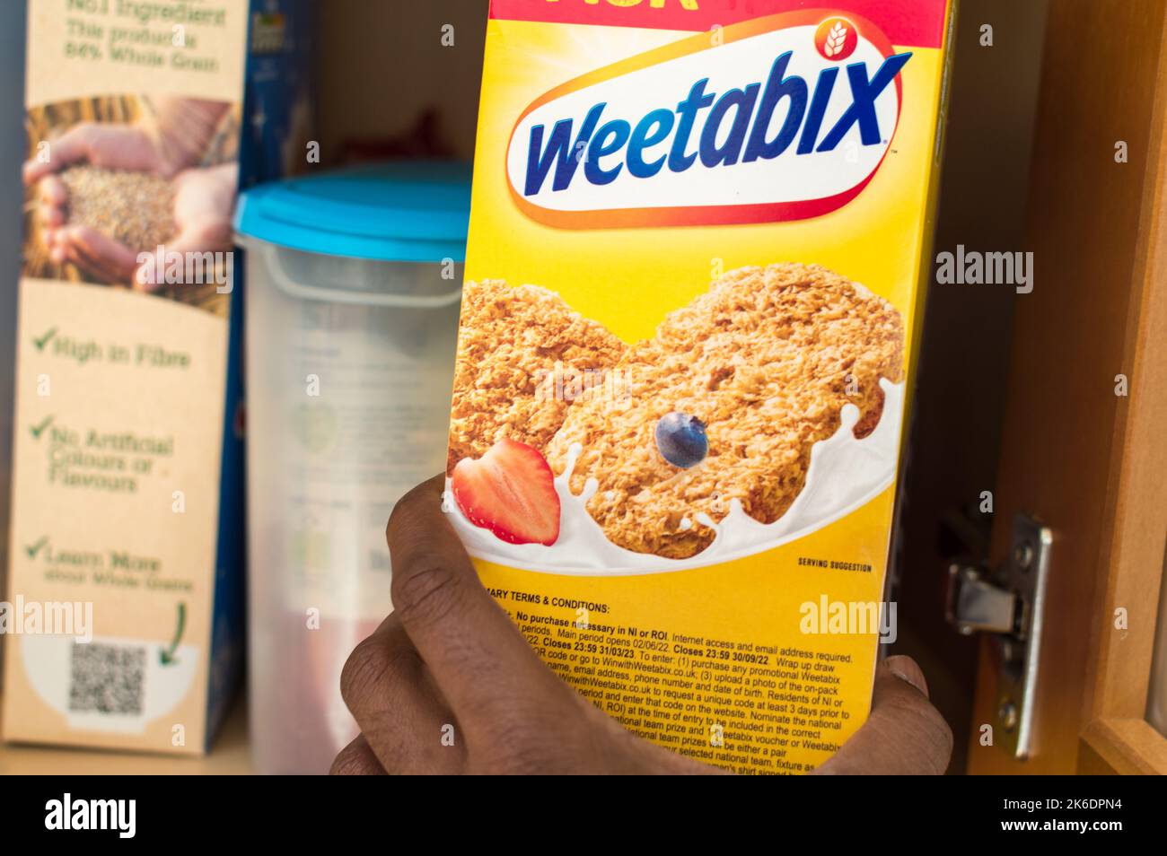 Adulte asiatique mâle cueillant une boîte de céréales dans un placard à aliments à la maison Banque D'Images