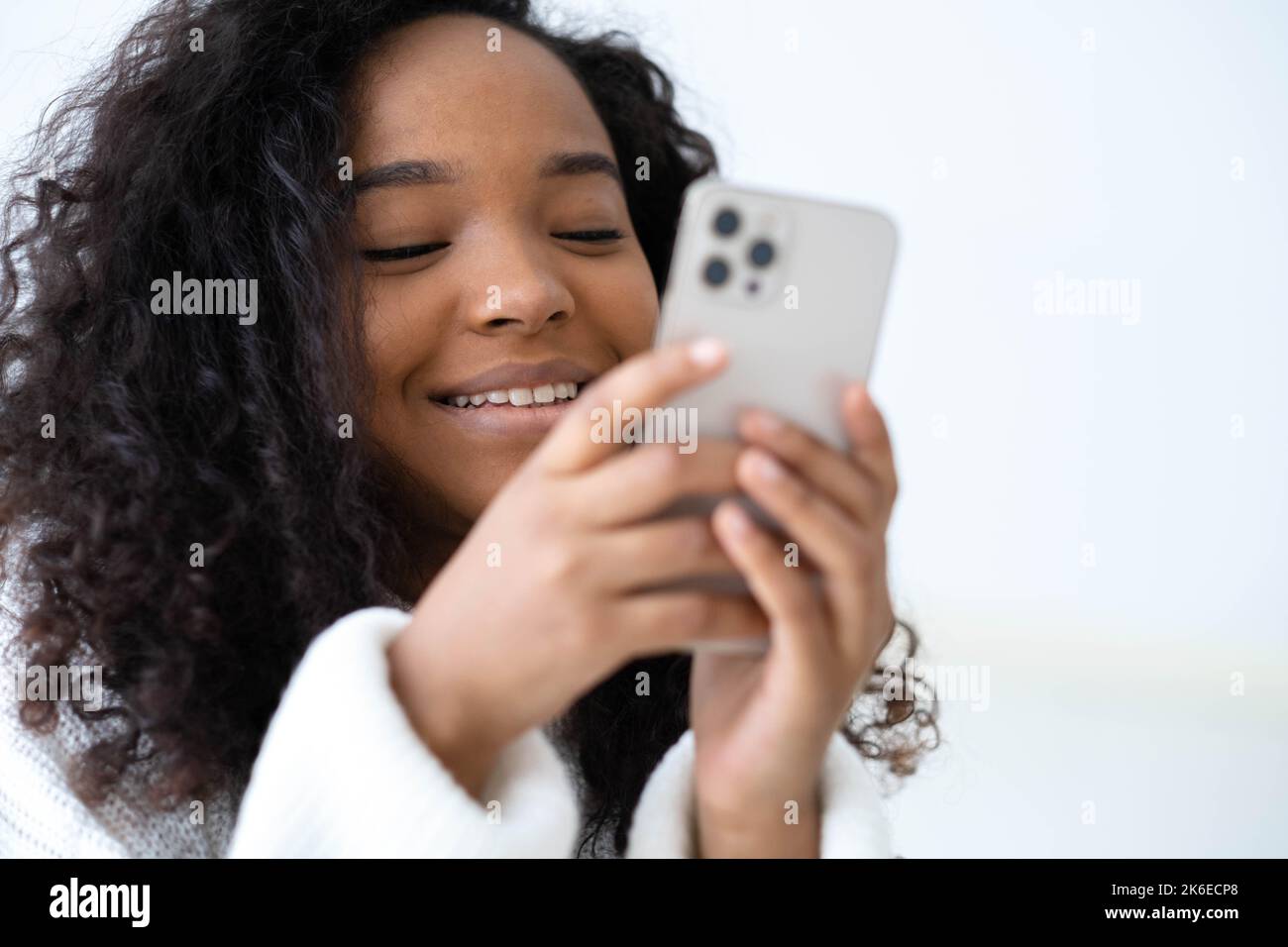 African American Girl utilisant iPhone 12 smartphone appuyer sur le doigt, lire les médias sociaux Internet, taper du texte ou acheter en ligne téléphone mobile en deux Banque D'Images