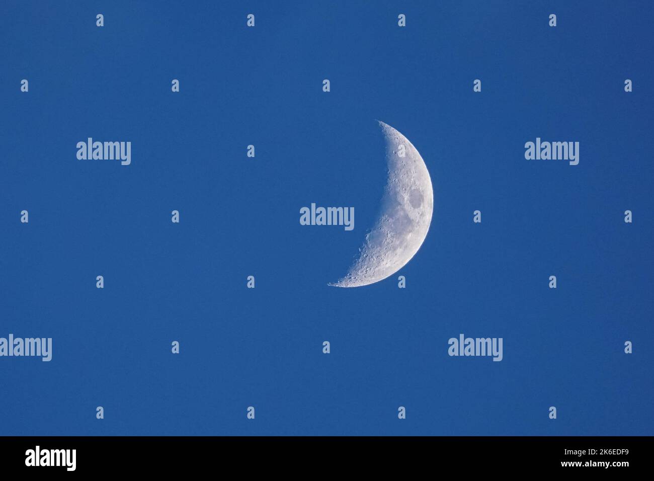 Croissant de lune cirant sur un ciel bleu foncé Banque D'Images