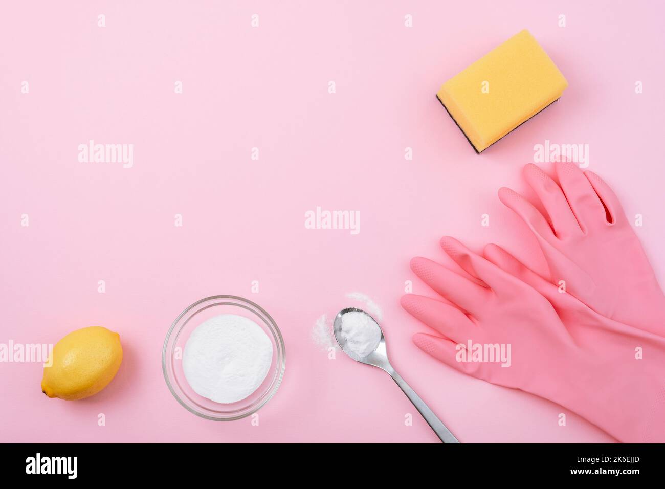 Gants de nettoyage, éponge jaune, bicarbonate de soude et citron sur fond rose. Concept de nettoyage écologique. Vue de dessus, plan d'agencement, espace de copie. Banque D'Images
