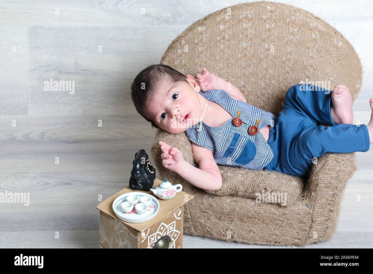 nouveau-né bébé garçon dans une belle robe couché sur une petite chaise, tabouret de petits jouets, expressions du visage, enfant arabe bébé, peau douce Banque D'Images