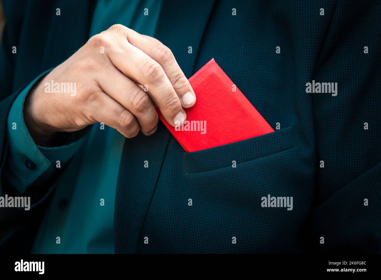 La carte d'identité rouge. Homme avec carte d'identité. Un homme d'affaires en costume bleu présente une carte d'identité rouge ou un pass. La main d'un homme dans un costume bleu prend un Banque D'Images