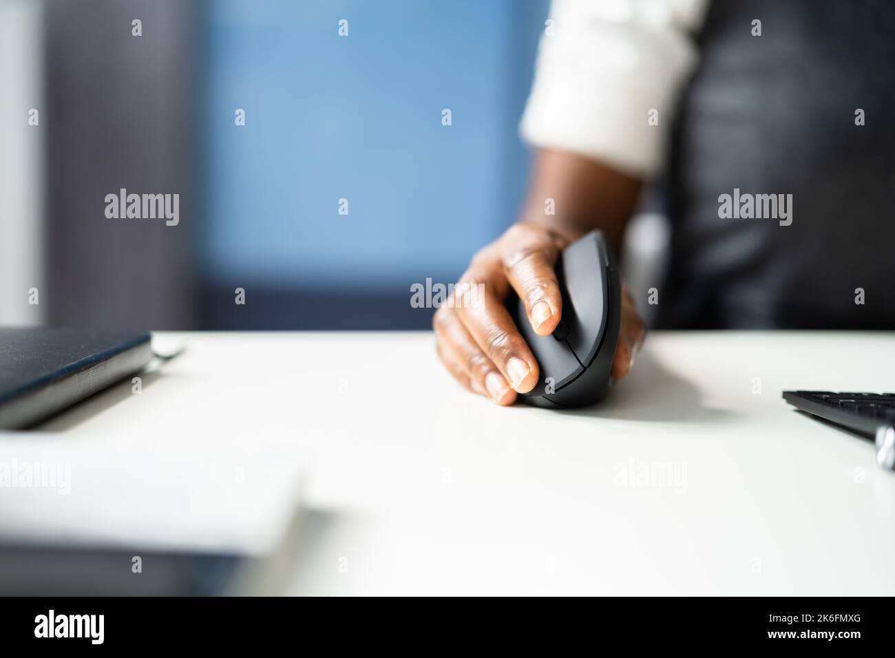 Femme afro-américaine avec douleur de poignet en utilisant la souris ergonomique verticale Banque D'Images