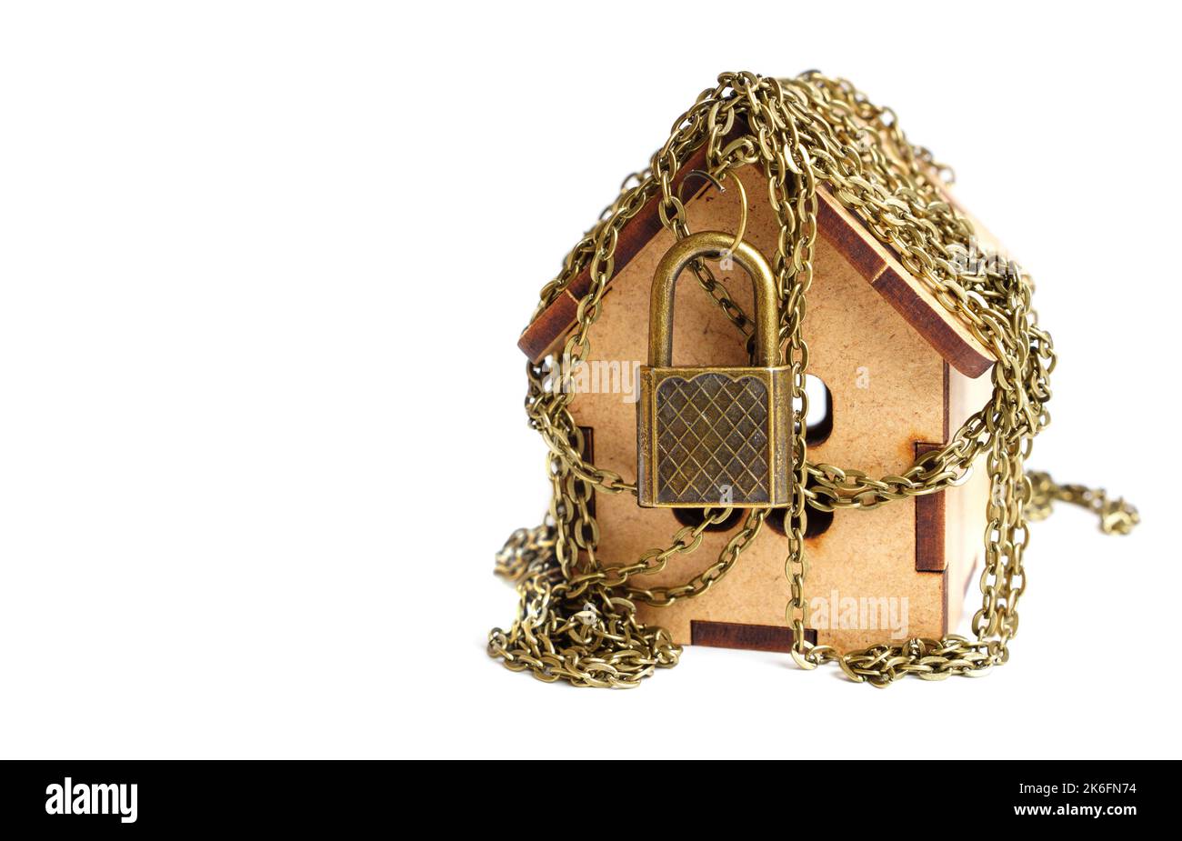 Maison de jouets enveloppée de chaînes et fixée avec un cadenas sur blanc. Banque D'Images