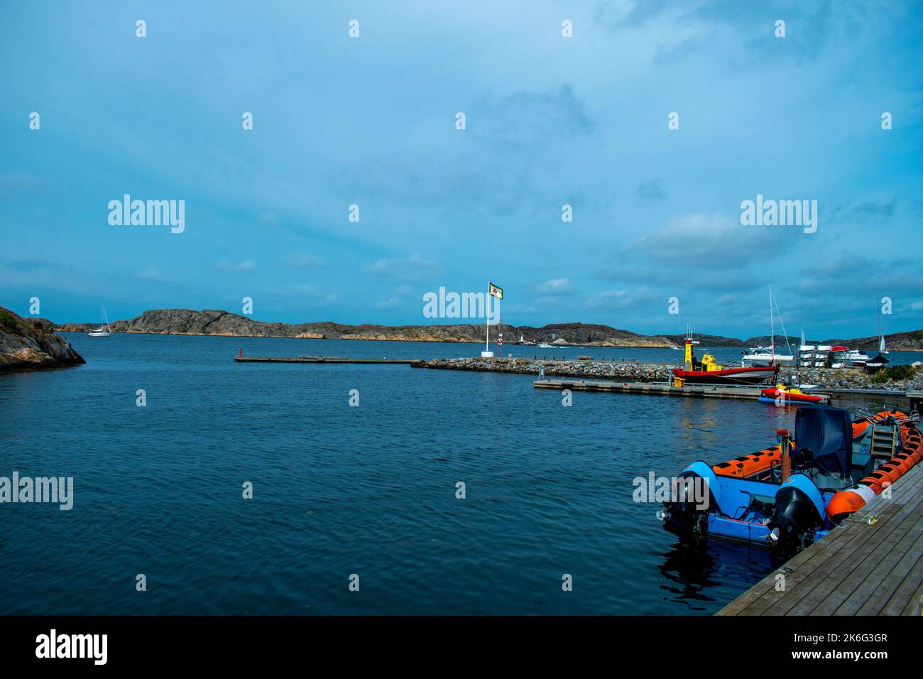 Un bateau gonflable vide dans l'eau bleue près de la rive sous ciel bleu nuageux Banque D'Images