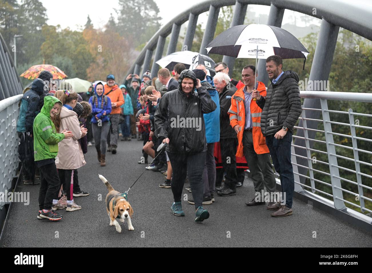 New Road, Kendal - 14 octobre 2022 - Minnie Ker, 61 ans d'Ayrshire, en Écosse, a été la première personne à marcher un chien (appelé Bassett) à travers le pont Gooseholme à Kendal, Minnie a déclaré: "C'était un honneur et un plaisir". Le pont a officiellement ouvert ses portes le vendredi 14 octobre par le président du conseil du comté de Cumbria (CCC), Cllr Andy Connell, avec des enfants de l'école de Stramongate à proximité (tous autorisés pour les photos). Le député Tim Farron a aussi fait une apparition. La passerelle, qui coûte 2 millions de livres, a remplacé un vieux pont plus petit qui a été endommagé à Storm Desmond qui a frappé la ville en 2015, causant des inondations dévastatrices. Le Banque D'Images