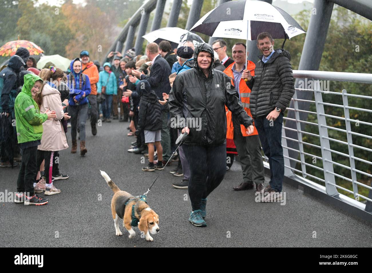 New Road, Kendal - 14 octobre 2022 - Minnie Ker, 61 ans d'Ayrshire, en Écosse, a été la première personne à marcher un chien (appelé Bassett) à travers le pont Gooseholme à Kendal, Minnie a déclaré: "C'était un honneur et un plaisir". Le pont a officiellement ouvert ses portes le vendredi 14 octobre par le président du conseil du comté de Cumbria (CCC), Cllr Andy Connell, avec des enfants de l'école de Stramongate à proximité (tous autorisés pour les photos). Le député Tim Farron a aussi fait une apparition. La passerelle, qui coûte 2 millions de livres, a remplacé un vieux pont plus petit qui a été endommagé à Storm Desmond qui a frappé la ville en 2015, causant des inondations dévastatrices. Le Banque D'Images