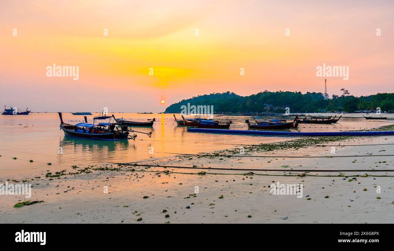 Coucher de soleil magique au-dessus du petit port avec de longs bateaux à queue à Ko Lipe Island, Thaïlande. L'île tropicale fait partie du parc naturel national de Tarutao. Lumière douce, Banque D'Images