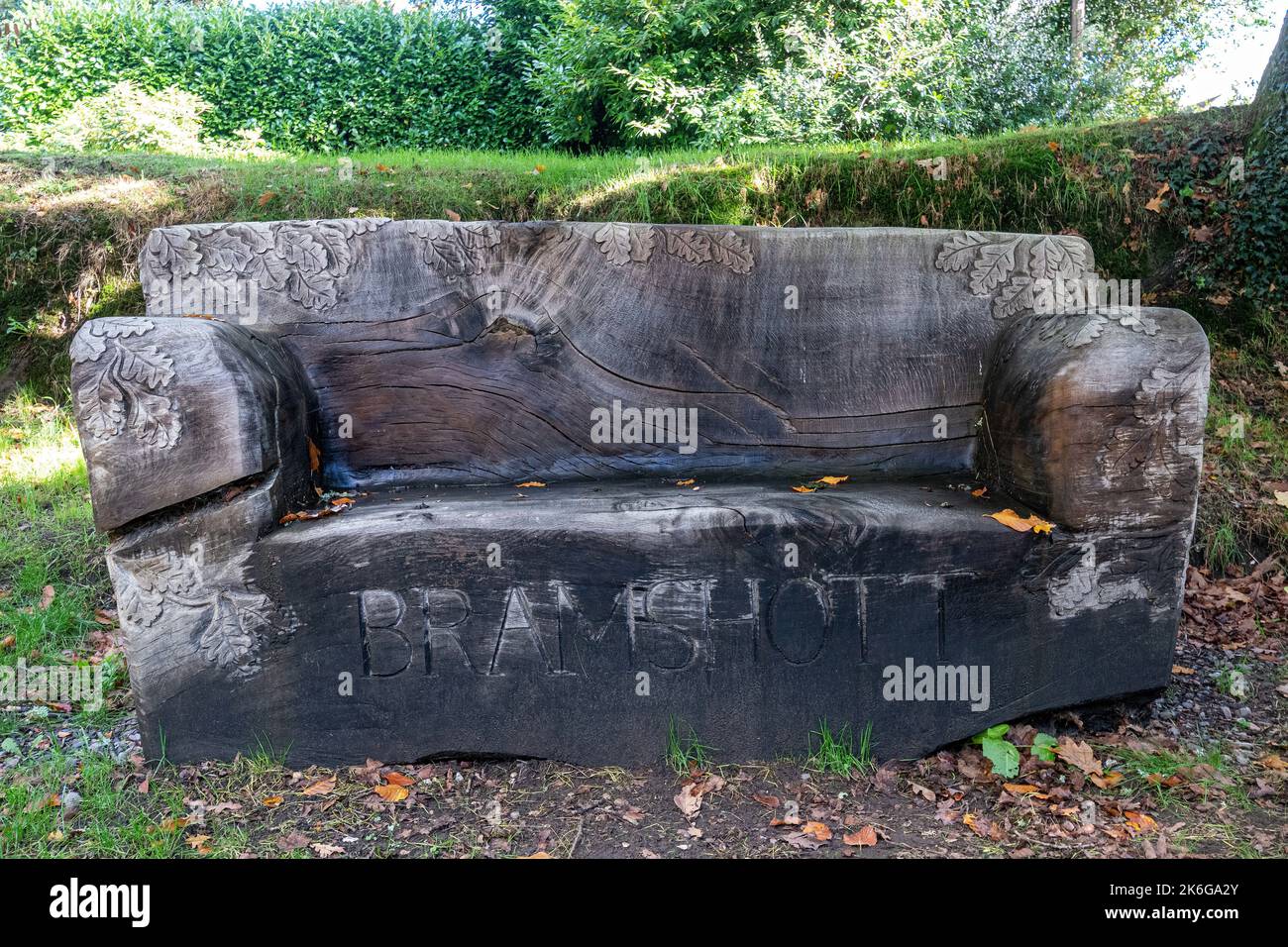 Banc en bois dans le village de Bramshott, Hampshire, Royaume-Uni, sculpté dans le chêne suspendu tombé près de l'église, appelé banc d'Adrian. Banque D'Images