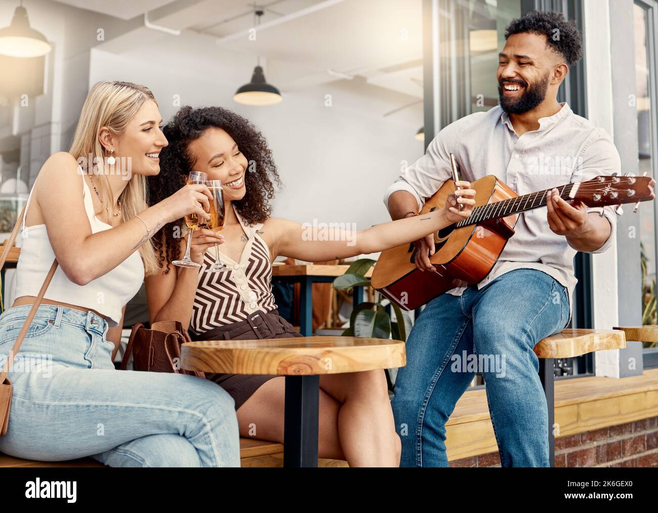 Le meilleur endroit avec une super ambiance. deux amis prenant des selfies ensemble dans un café tandis qu'un homme joue de la guitare. Banque D'Images