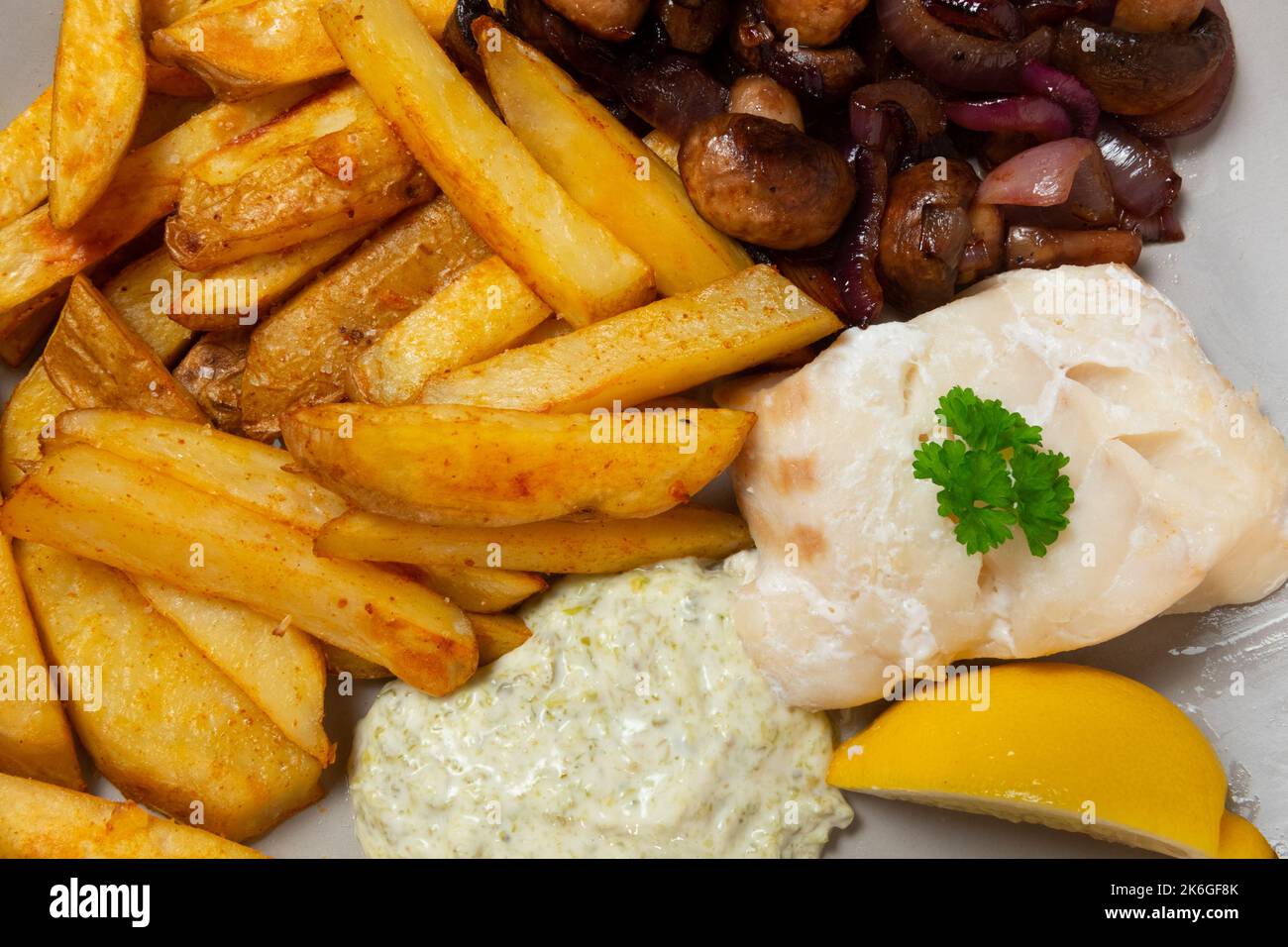 Gros plan du filet de morue cuit, de la peau sur les croustilles, des champignons sautés et de l'oignon rouge, de la sauce tartare Banque D'Images