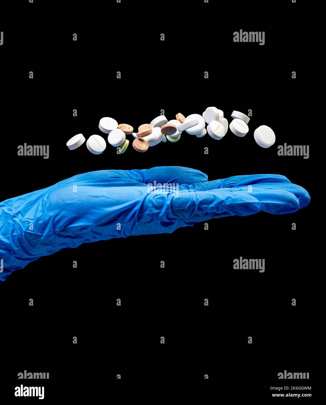 Pilules médicales sur un fond noir isolé avec réflexion abandonnée de la main Banque D'Images
