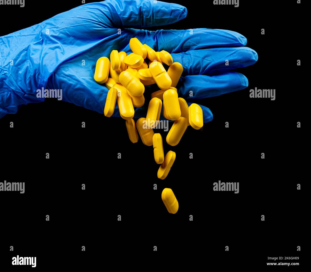 Pilules médicales sur un fond noir isolé avec réflexion abandonnée de la main Banque D'Images