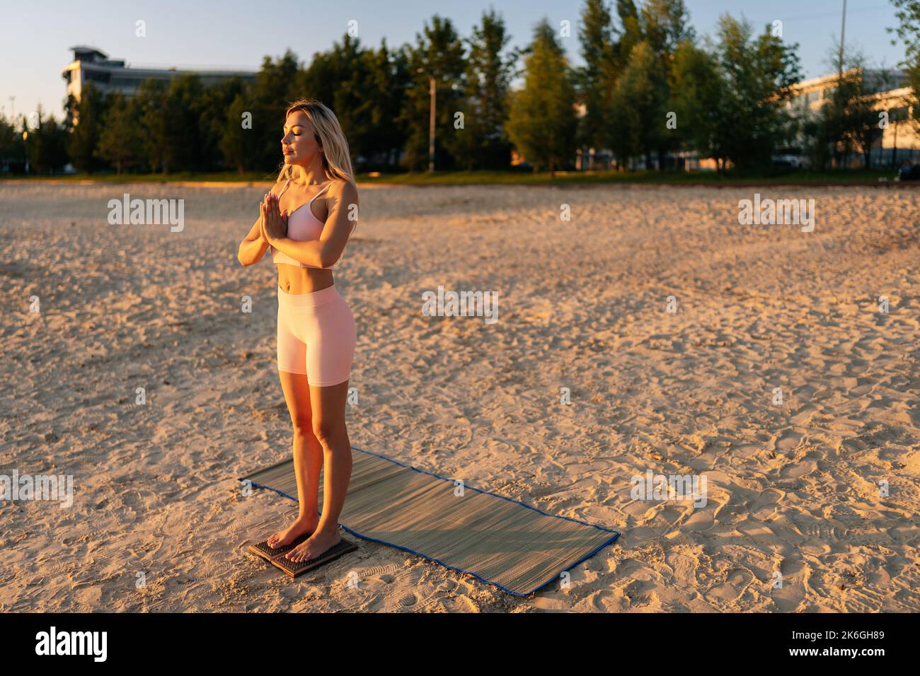 Portrait d'une jeune femme yogini debout sur le panneau de l'ongle Sadhu faisant signe de main namaste pendant la pratique de méditation de concentration sur la plage de sable. Banque D'Images
