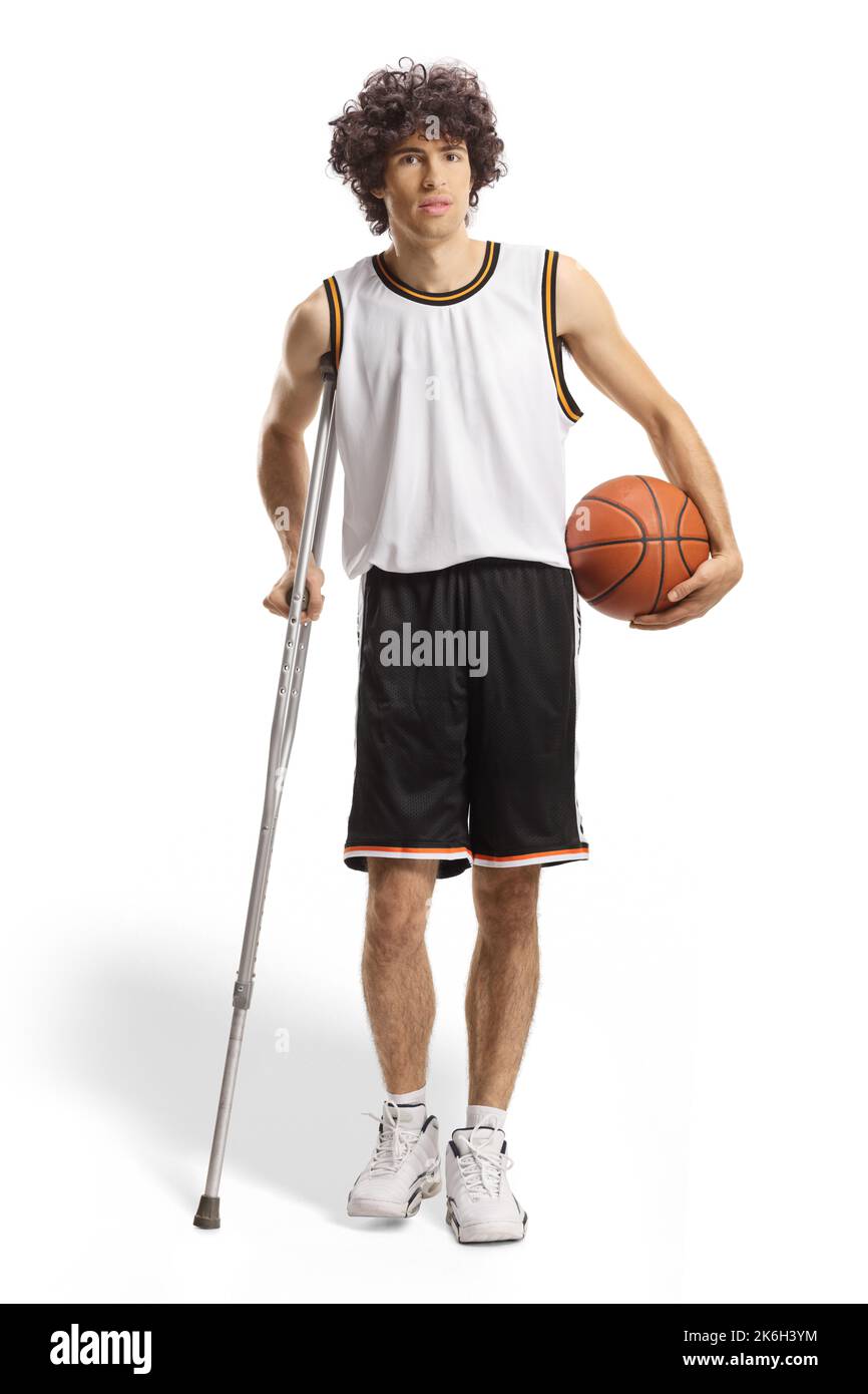 Joueur de basket-ball tenant une balle et marchant avec une béquille isolée sur fond blanc Banque D'Images
