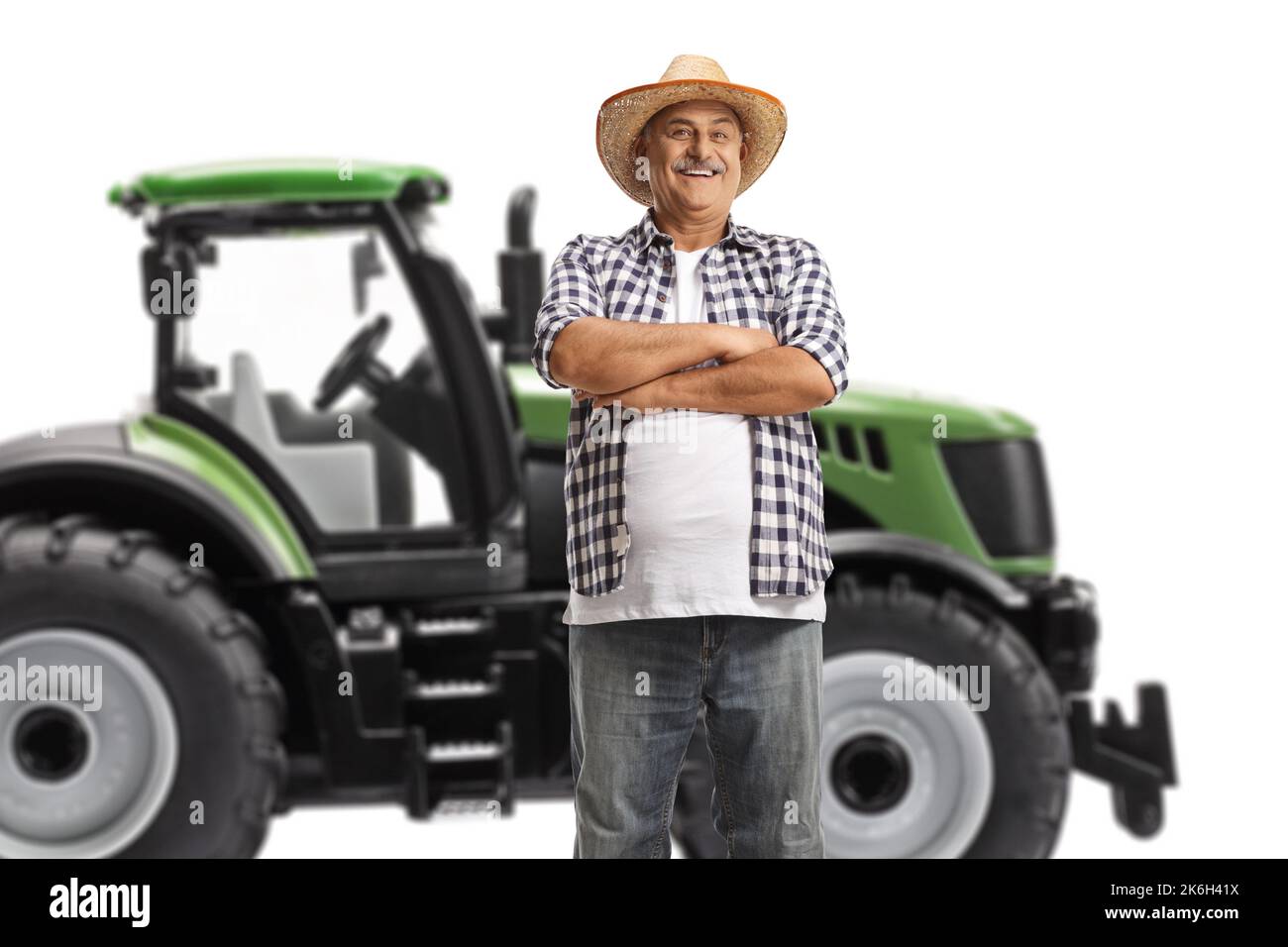 Agriculteur mûr debout devant un tracteur vert isolé sur fond blanc Banque D'Images