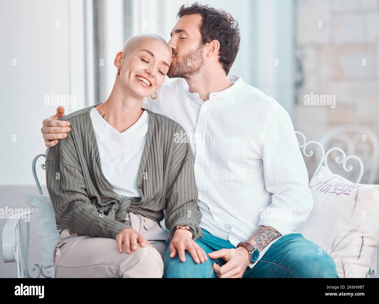 Un jeune couple caucasien affectueux s'embrasse tout en se relaxant à la maison. Joyeux petit ami embrassant et embrassant petite amie sur la tête pendant Banque D'Images