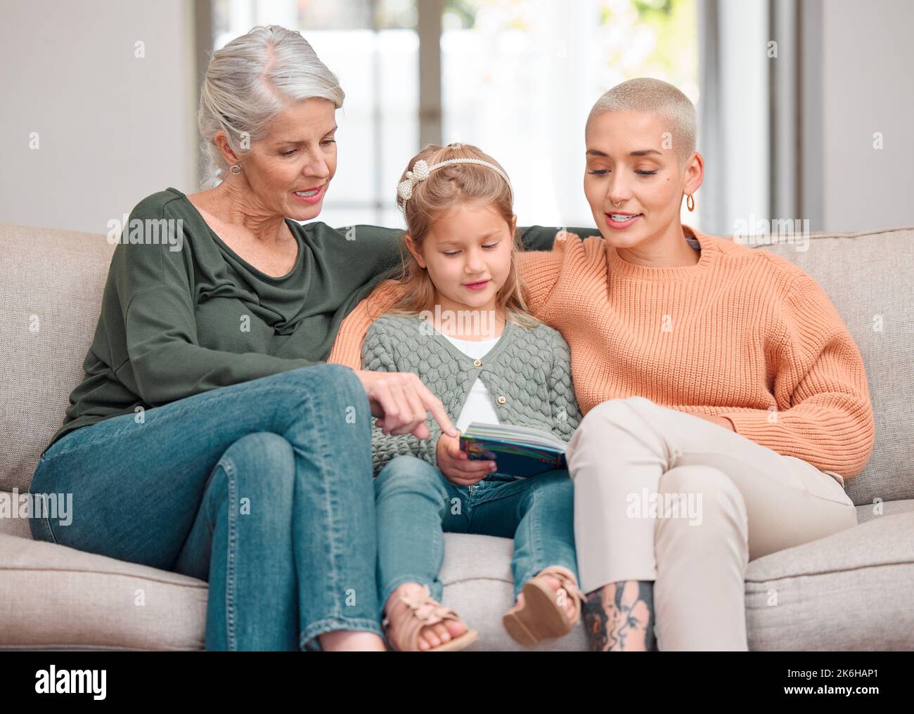Elle aime nous lire. une femme mûre se liant avec sa fille et sa petite-fille tout en utilisant une tablette numérique. Banque D'Images