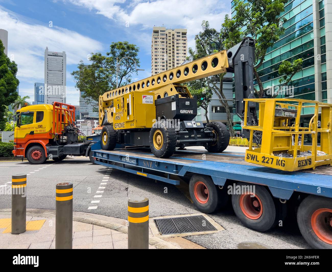 Un immense camion de transport transporte un équipement de levage de rampe sur la route, ce qui se transforme en une petite route difficile avec précaution. Banque D'Images