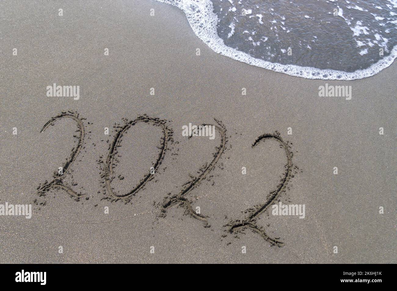 Chiffres de 2022 sur la mer, un message manuscrit sur le sable avec des bulles de mousse sur la plage. Concept de l'année sortante. Banque D'Images