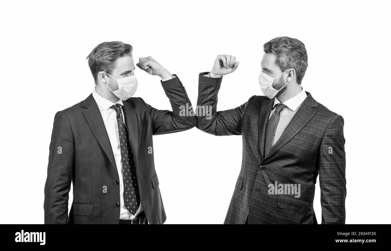 les hommes d'affaires en masque se cognent les coudes au lieu de serrer les mains pour éviter le contact, salutation d'affaires. Banque D'Images