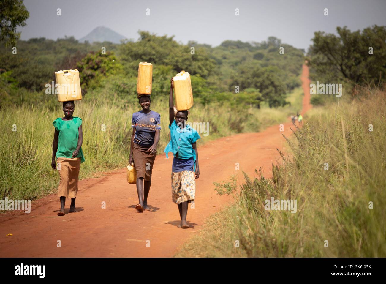 Une fille et deux femmes marchent sur une longue distance pour apporter de l'eau à leur maison dans le district d'Abim, en Ouganda, en Afrique de l'est. Banque D'Images