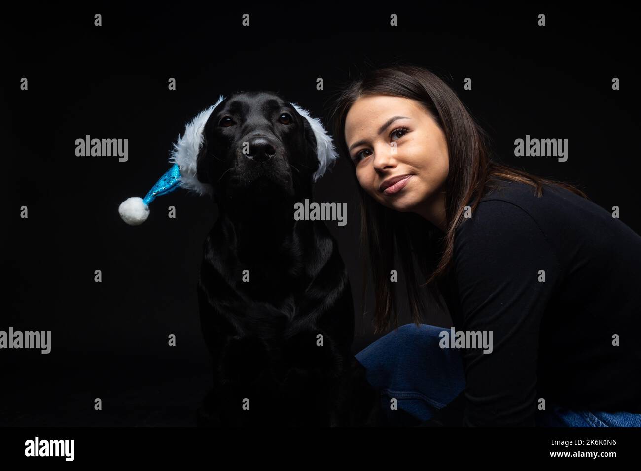 Une fille tient un chien Labrador Retriever dans ses bras. Prise en gros plan dans un studio photo, sur un dos noir Banque D'Images