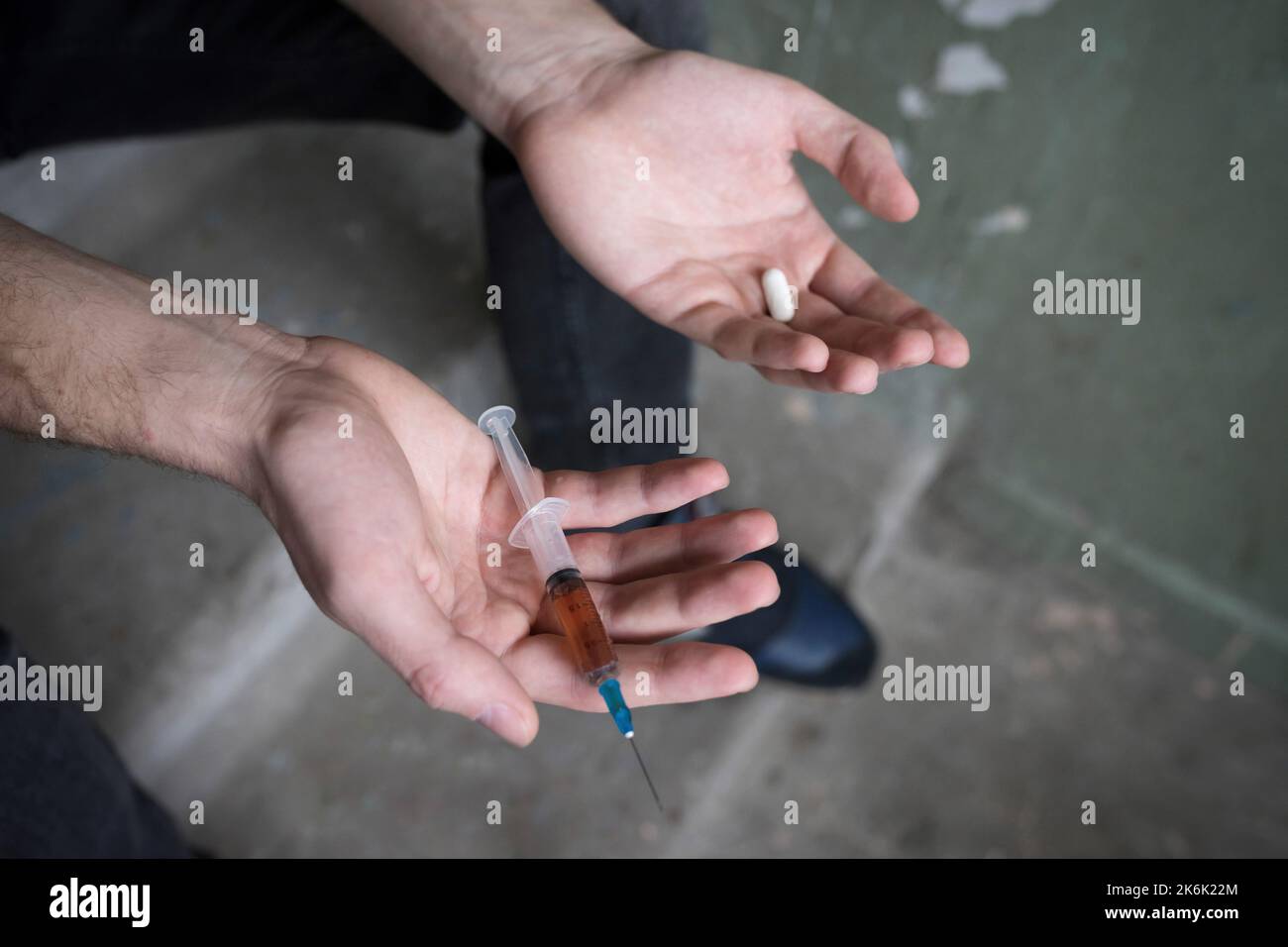 Seringue et comprimé dans les mains d'un addict, gros plan. Concept de dépendance. Banque D'Images