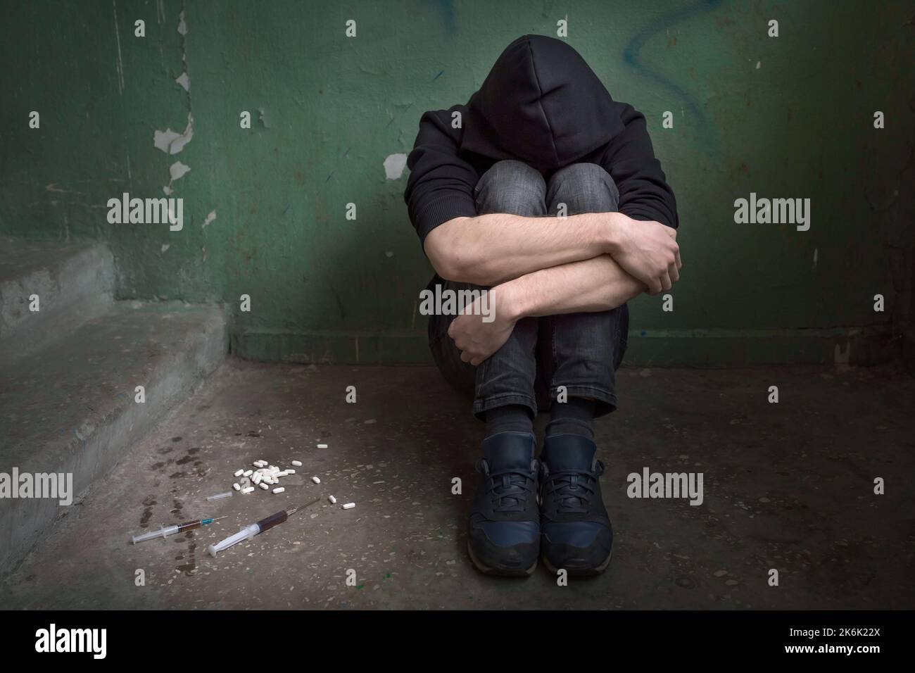 Un jeune drogué avec des armes pliées dans une maison abandonnée. Homme éprouvant une crise de toxicomanie, dépression. Concept de dépendance. Banque D'Images