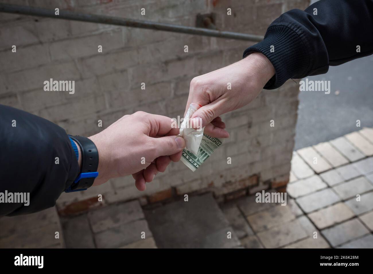 La main d'un drogué avec de l'argent, achète de la cocaïne ou de l'héroïne à un marchand. Concept de vente de médicaments. Banque D'Images