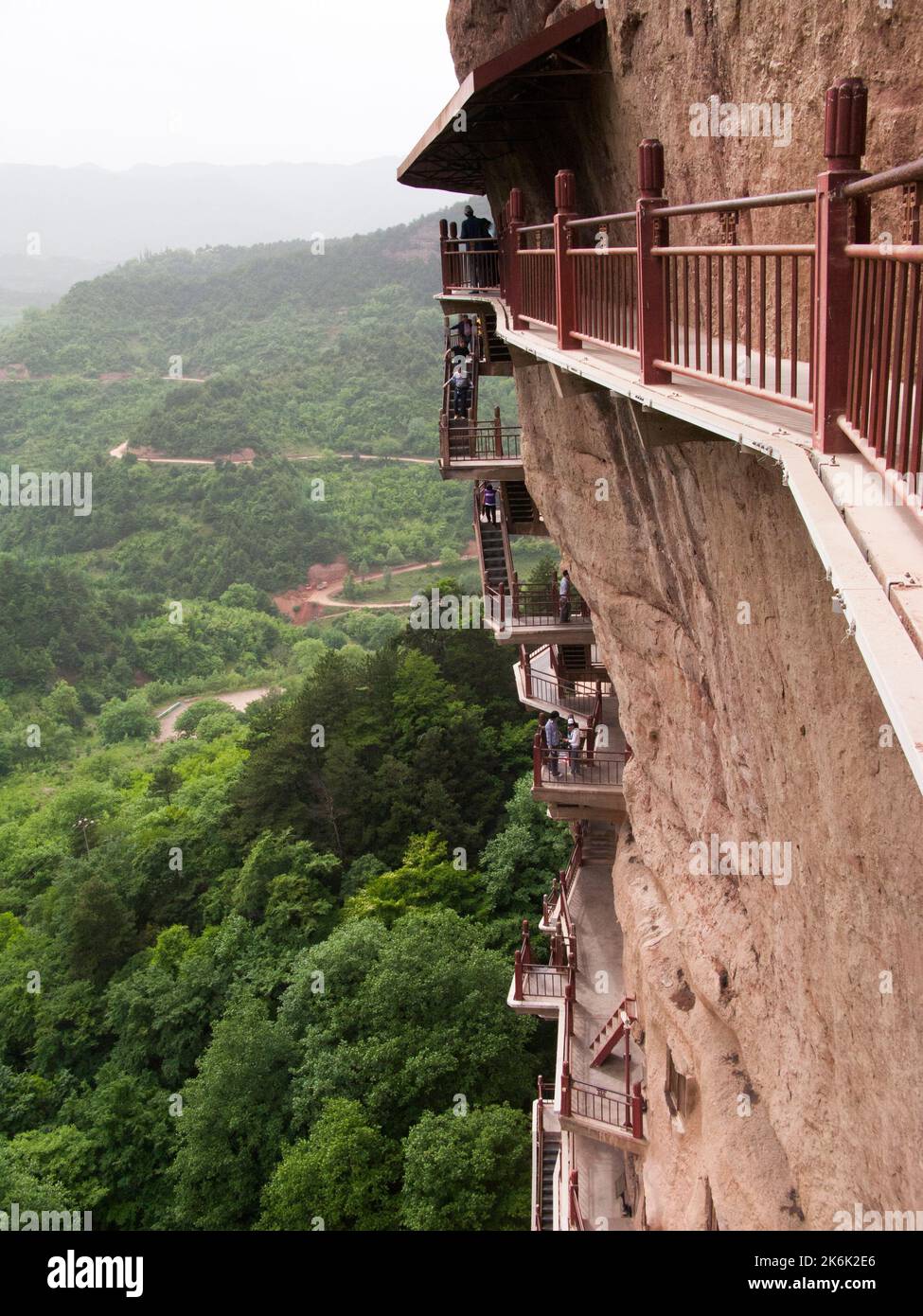Les escaliers et la gravité défiant la grande passerelle / escaliers et les allées attachées à la roche fine ont permis aux visiteurs de contact étroit avec les figures d'argile et les anciennes sculptures en pierre. Le site de représentations / figures bouddhistes représentations et d'images de Bouddha (certaines semblent être très récemment restaurées en béton) sur la face rocheuse des Grottes de Maijishan, autrefois romanisé comme Maichishan, une série de 194 grottes coupées sur le côté des montagnes de Majishan à Tianshui, province de Gansu, Chine. PRC. (67/125) Banque D'Images