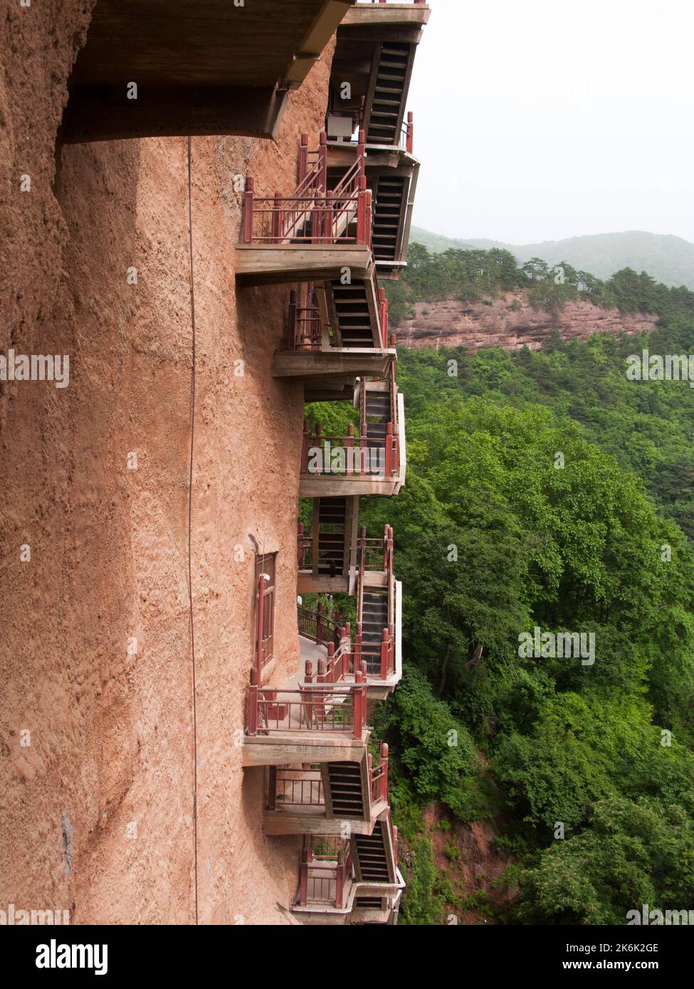 Les escaliers et la gravité défiant la grande passerelle / escaliers et les allées attachées à la roche fine ont permis aux visiteurs de contact étroit avec les figures d'argile et les anciennes sculptures en pierre. Le site de représentations / figures bouddhistes représentations et d'images de Bouddha (certaines semblent être très récemment restaurées en béton) sur la face rocheuse des Grottes de Maijishan, autrefois romanisé comme Maichishan, une série de 194 grottes coupées sur le côté des montagnes de Majishan à Tianshui, province de Gansu, Chine. PRC. (67/125) Banque D'Images