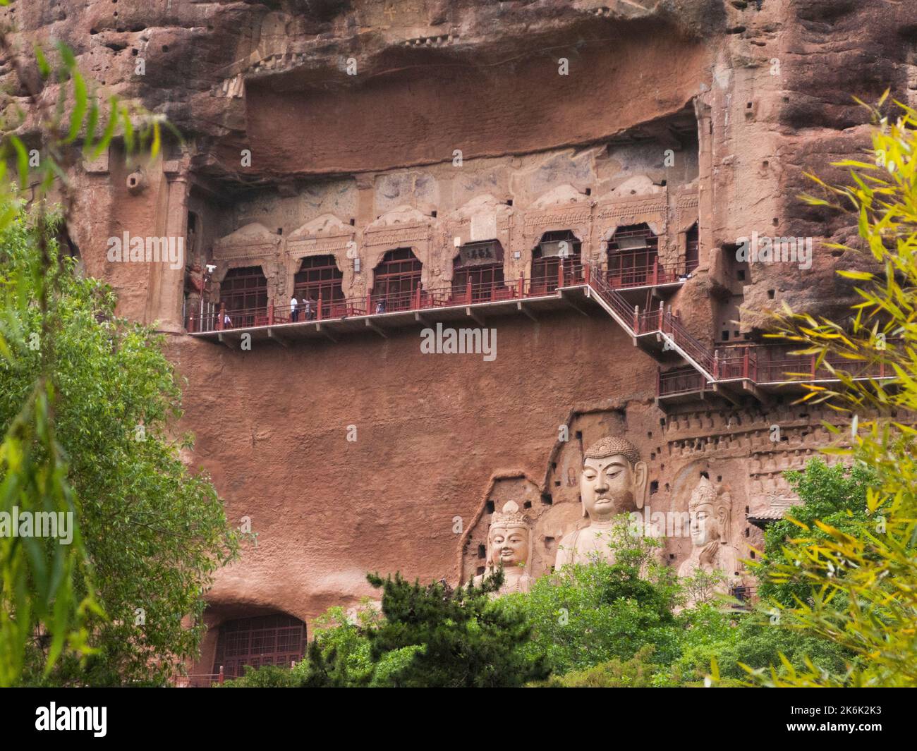 Les escaliers et la gravité défiant la grande passerelle / escaliers et les allées attachées à la roche fine ont permis aux visiteurs de contact étroit avec les figures d'argile et les anciennes sculptures en pierre. Le site de représentations / figures bouddhistes représentations et d'images de Bouddha (certaines semblent être très récemment restaurées en béton) sur la face rocheuse des Grottes de Maijishan, autrefois romanisé comme Maichishan, une série de 194 grottes coupées sur le côté des montagnes de Majishan à Tianshui, province de Gansu, Chine. PRC. (67/126) Banque D'Images