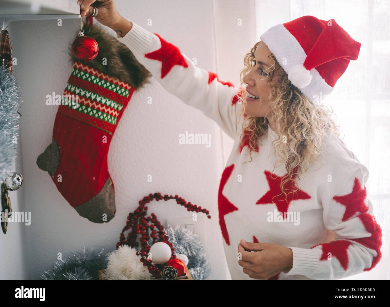 Femme gaie sourire et profiter de décorer appartement avec des décorations de noël. Les jeunes femmes portent le chapeau du père noël et s'amusent pendant le ho de décembre Banque D'Images