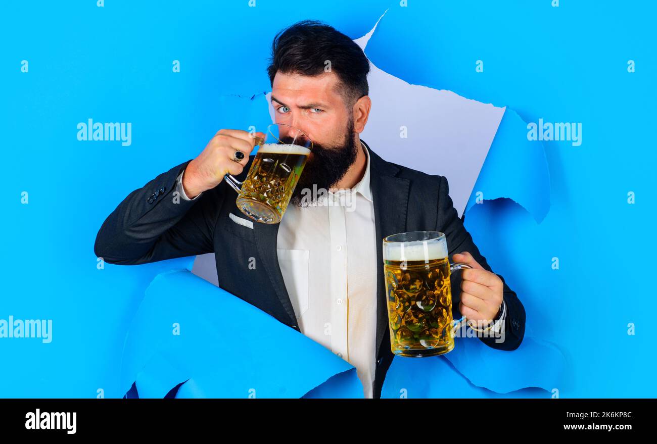 Oktoberfest. Homme barbu de la bière regardant à travers le trou de papier. Homme élégant avec mugs of ALE. Banque D'Images