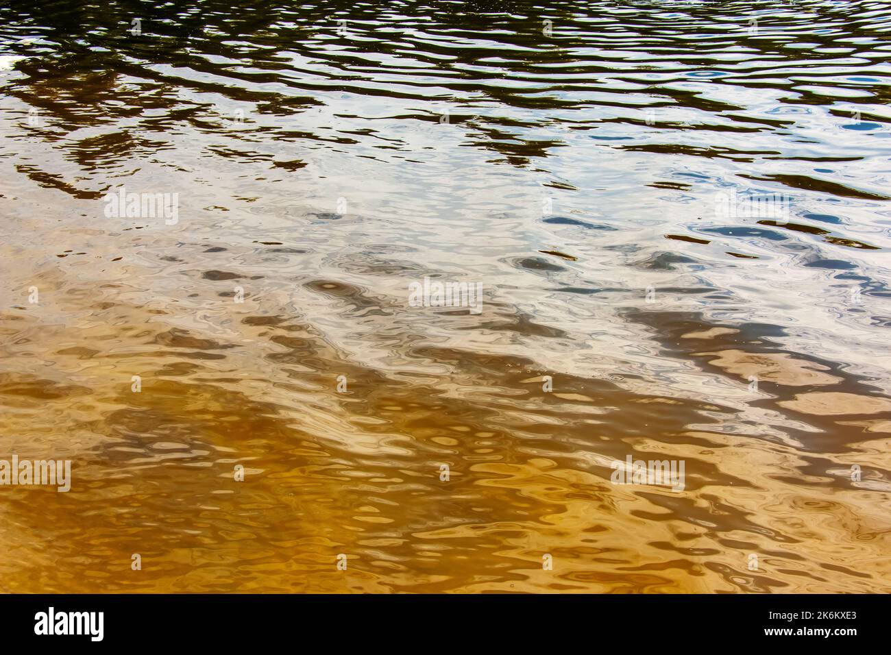 Fond de texture d'ondulation d'eau. Surface d'eau ondulée au coucher du soleil, lumière dorée se reflétant dans l'eau. Banque D'Images