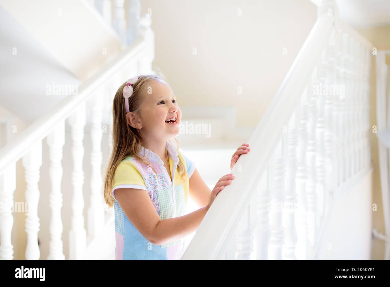 Escaliers de marche pour enfants dans la maison blanche. Petite fille jouant dans un escalier ensoleillé. La famille se déplace dans une nouvelle maison. Escalier moderne pour les enfants. Banque D'Images