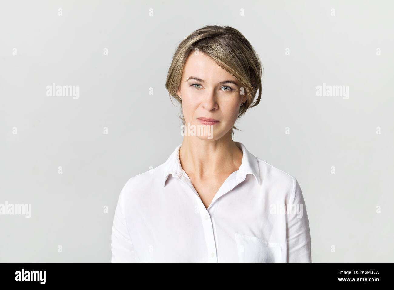 Femme d'affaires sérieuse debout. Femme de confiance en chemise blanche isolée sur blanc Banque D'Images