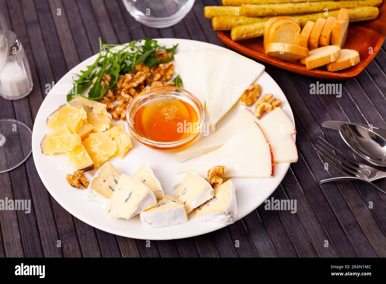 Différents types de fromage tranchés et servis sur une assiette avec un bol de miel, des noix Banque D'Images