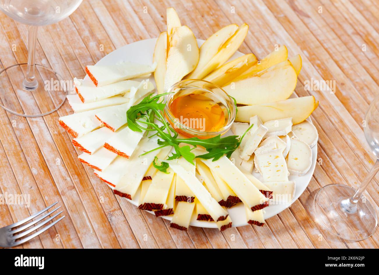Assiette avec différents types de fromage et une tasse de miel Banque D'Images