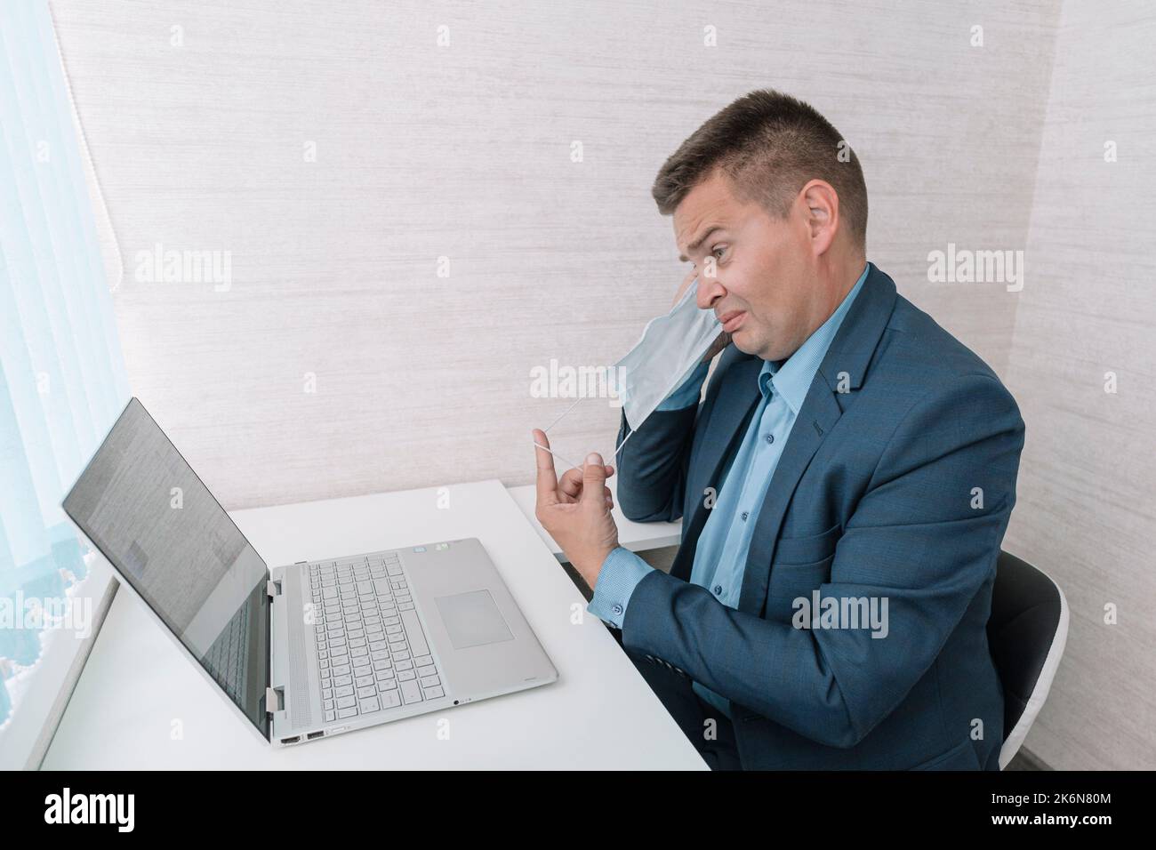 l'homme retire son masque de protection sur fond blanc. La fin de la pandémie du coronavirus. La quarantaine est terminée. fatigue liée au port d'un masque. Banque D'Images