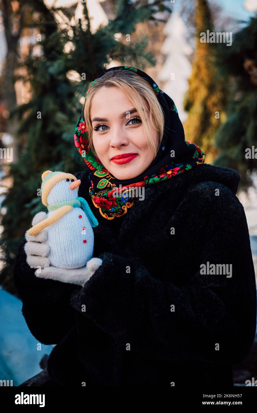 Belle jeune femme dans un foulard ukrainien national tient un bonhomme de neige Banque D'Images