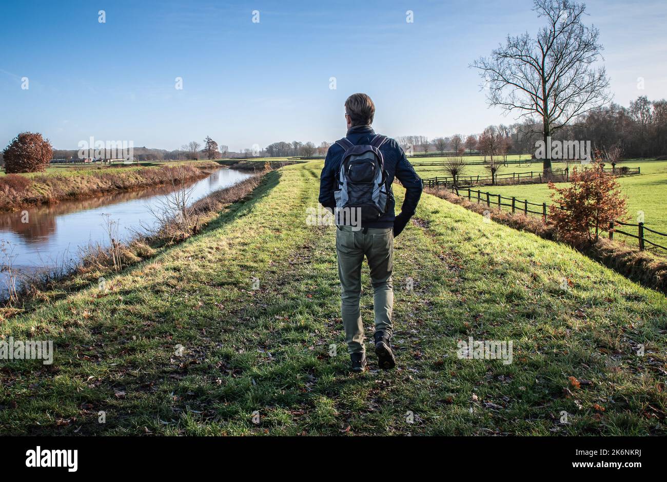 Randonneur mâle avec sac à dos marchant seul sur le chemin de l'herbe en automne. Banque D'Images