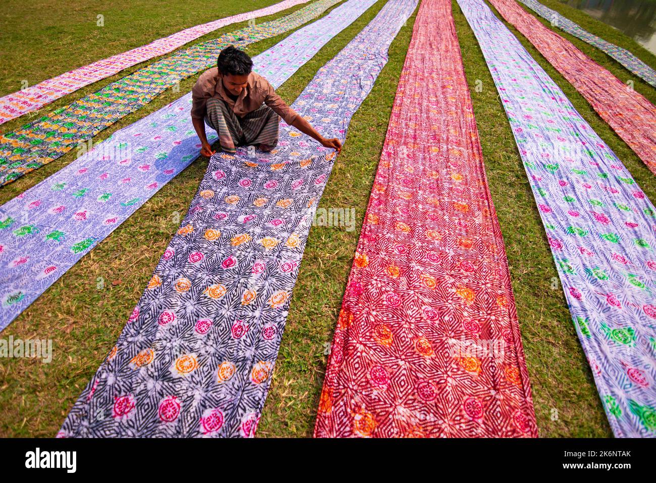 Les employés sèchent des chiffons colorés en rangées nettes sur un champ. Les tissus sont localement appelés 'Saree' - un vêtement traditionnel pour les femmes. Banque D'Images