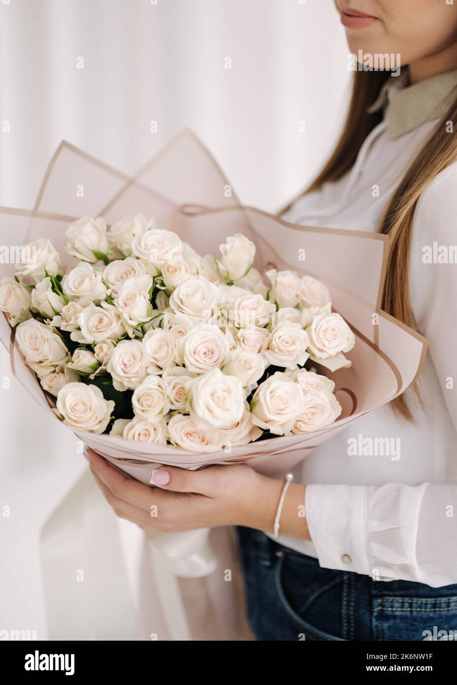 Une fille tient un bouquet de fleurs blanches dans un emballage cadeau. reses Banque D'Images