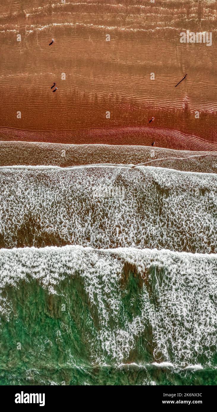 Vue aérienne des vagues vertes qui se brisent sur Dark Red Beach Banque D'Images