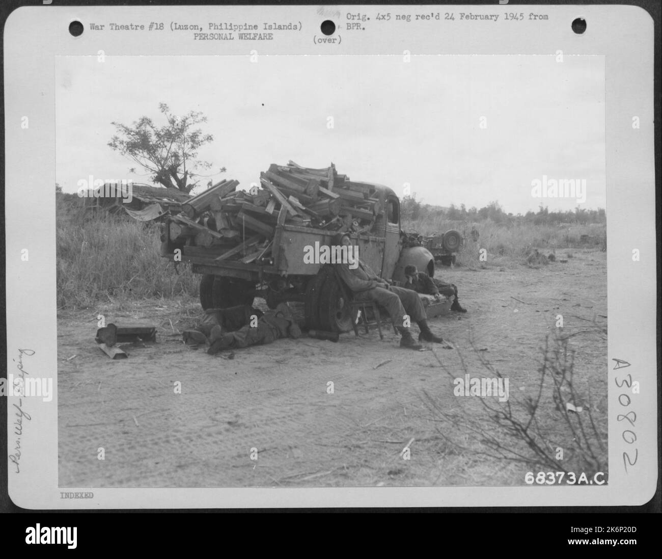 Épuisé après des heures de combats acharnés sur les collines surplombant Clark Field, Luzon, les îles Philippines, « GI's » a saisi l'occasion de se reposer contre un camion de Jap renversé. Le sommeil est venu à des heures irrégulières et le travail éprouvant d'un pied-soldat a pris Banque D'Images